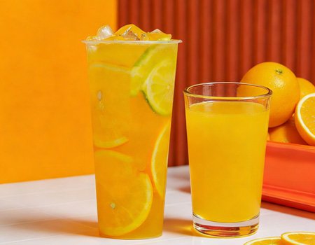 On the table are oranges, a cup of fruit tea made from oranges, and a cup of concentrated fruit juice