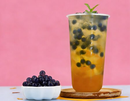 On the table at once, there is a small cup of bursting pearls, and a cup of fruit tea containing bursting pearls