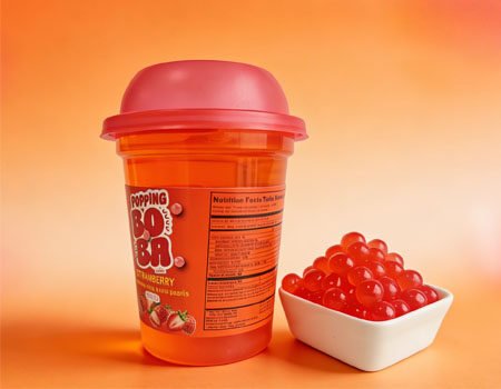 a cup of boba drinks, with a bowl of popping boba next to it