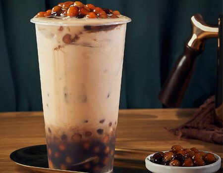 a cup of bubble tea with tapioca pearls,a small bowl of tapioca pearls next to it