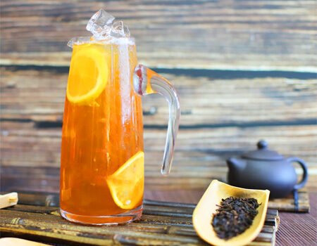 There is a teapot on the table, some tea leaves, and a cup of fruit tea
